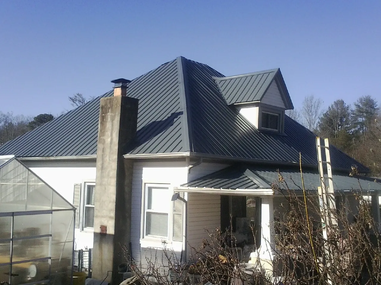 Dark blue standing seam metal roof on a white farmhouse with dormer — Slate & Tile Roof Repair by Roofing Brothers in Murray