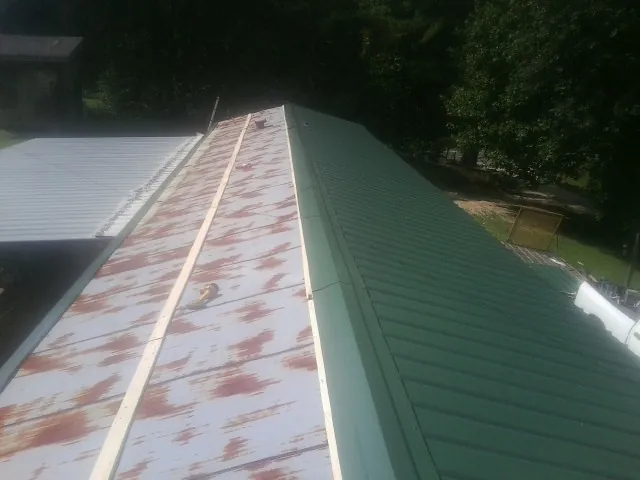 Old rusted panels beside newly installed green metal roofing — Wind Damage Roof Repair by Roofing Brothers in Murray