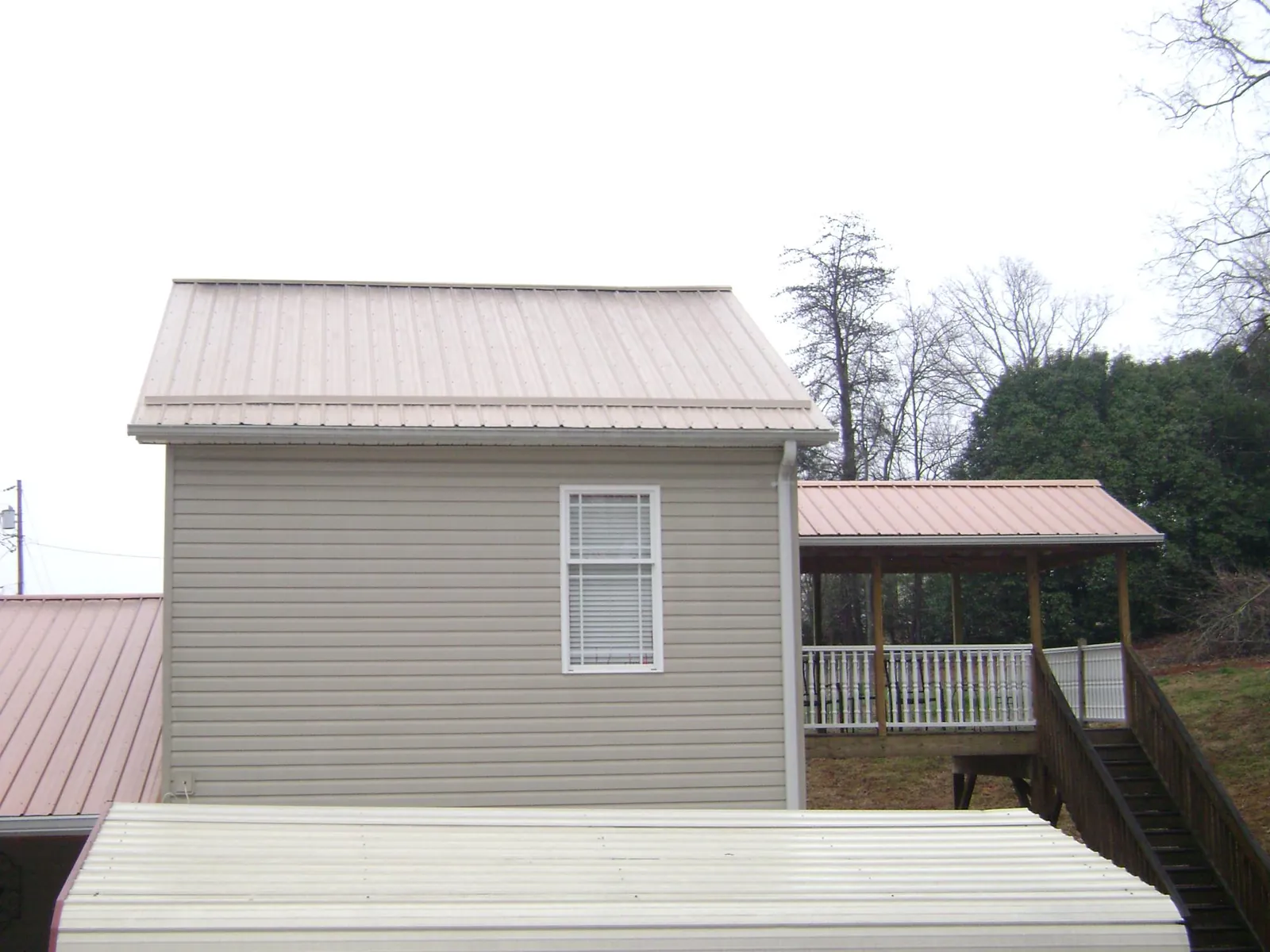 Tan metal roofs on a two story addition and attached porch, from a Roof Replacement job in Murray