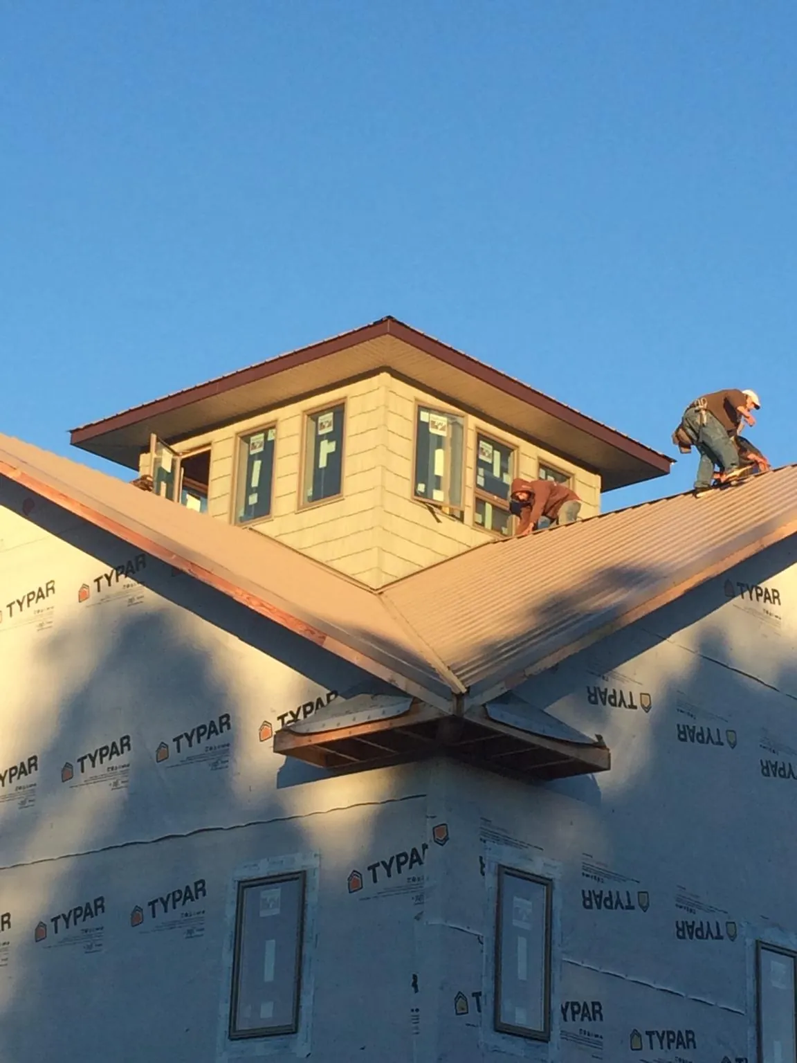 Roofers working around a rooftop cupola on a new metal roof at sunset — Roof Waterproofing in Murray by Roofing Brothers